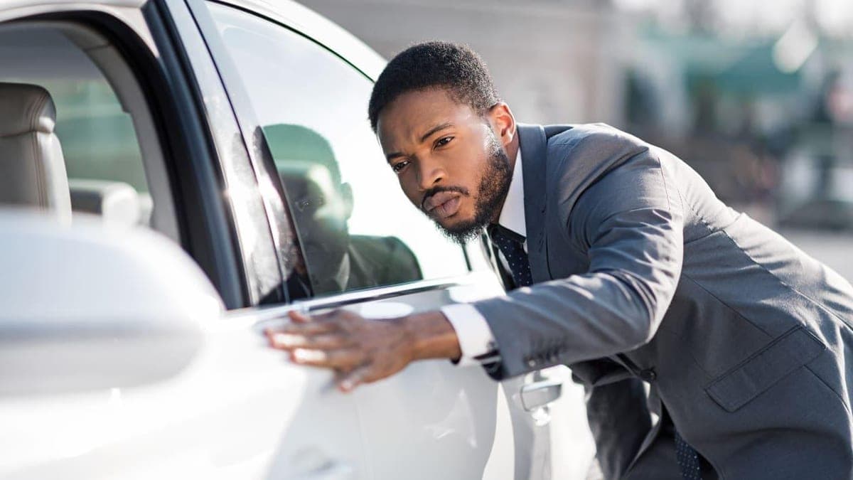 Buyer reviewing a used car's service history book at a dealership