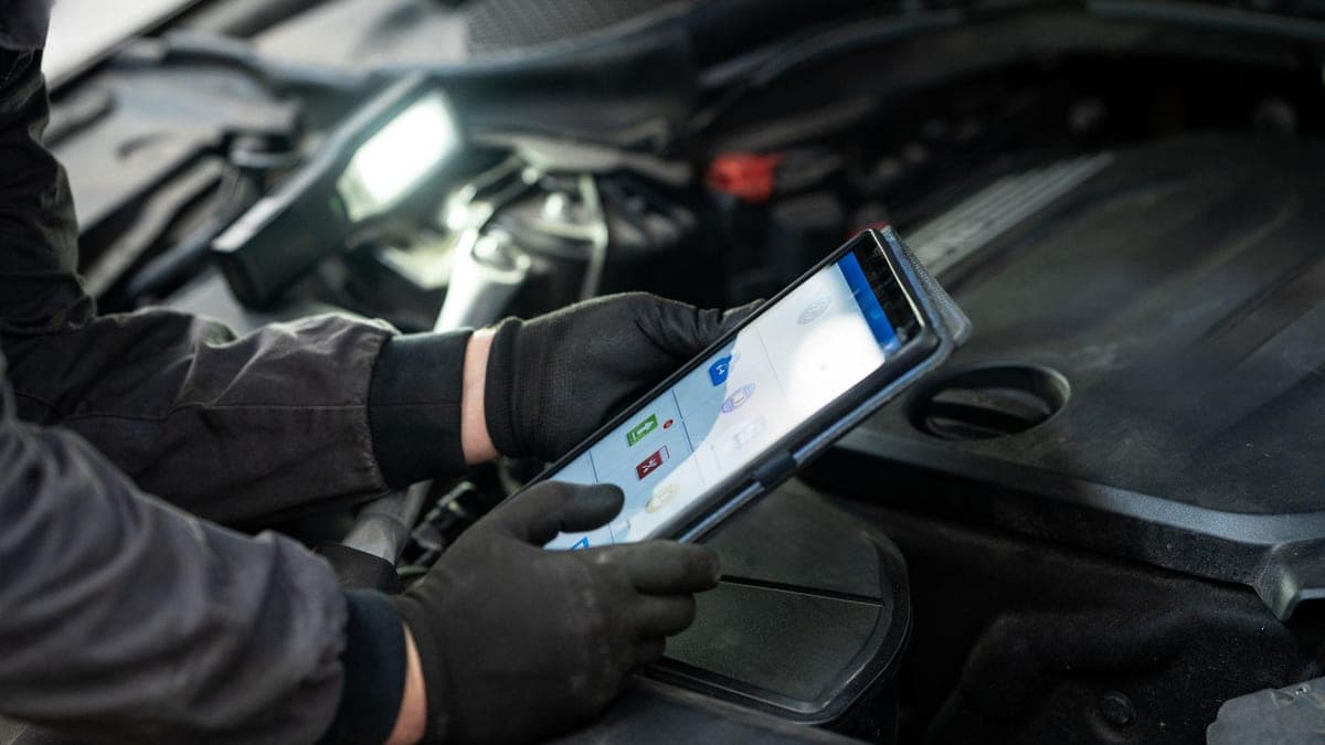 A motor trader inspecting a vehicle at a car auction with paperwork in hand